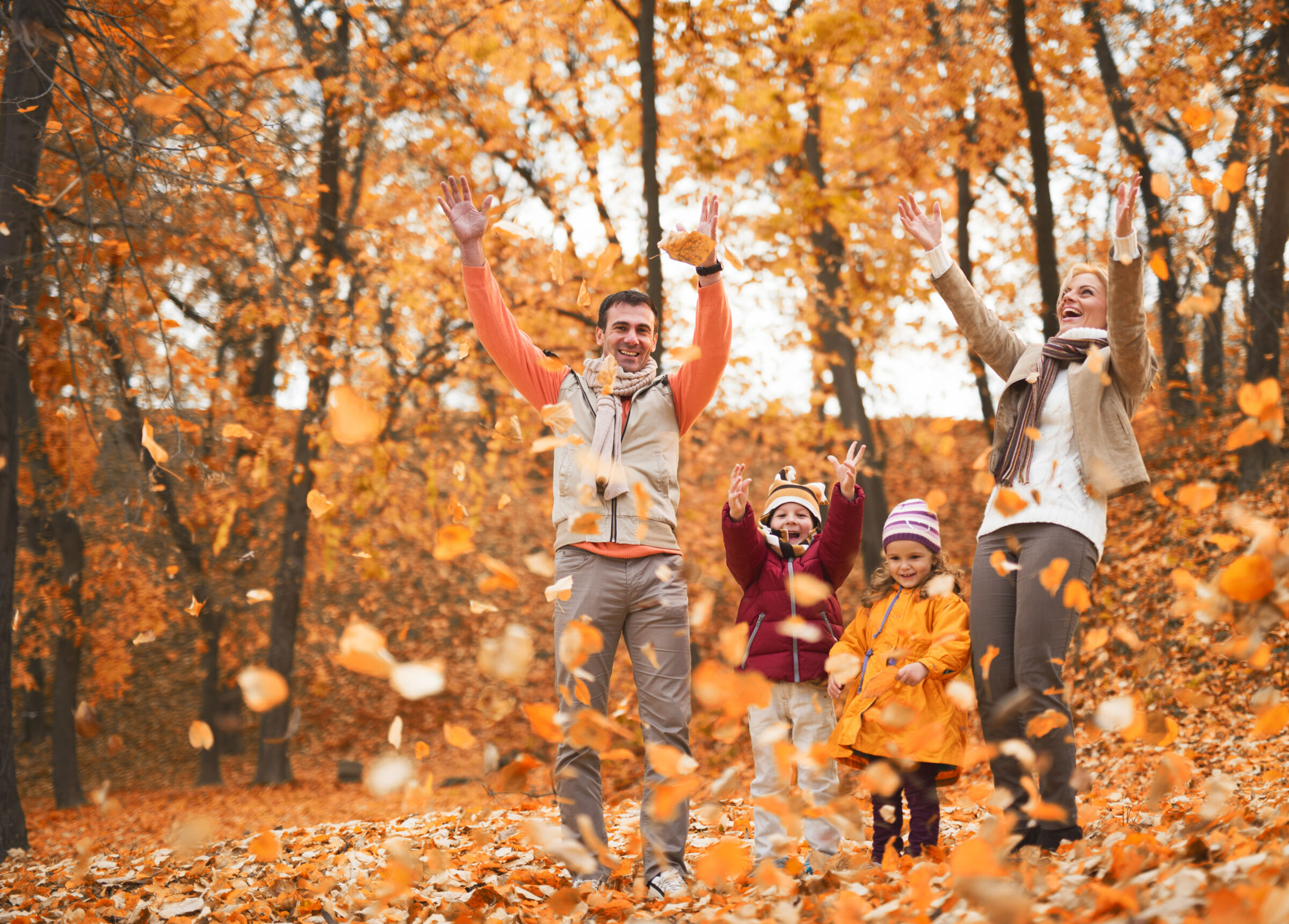 Family playing in fall leaves