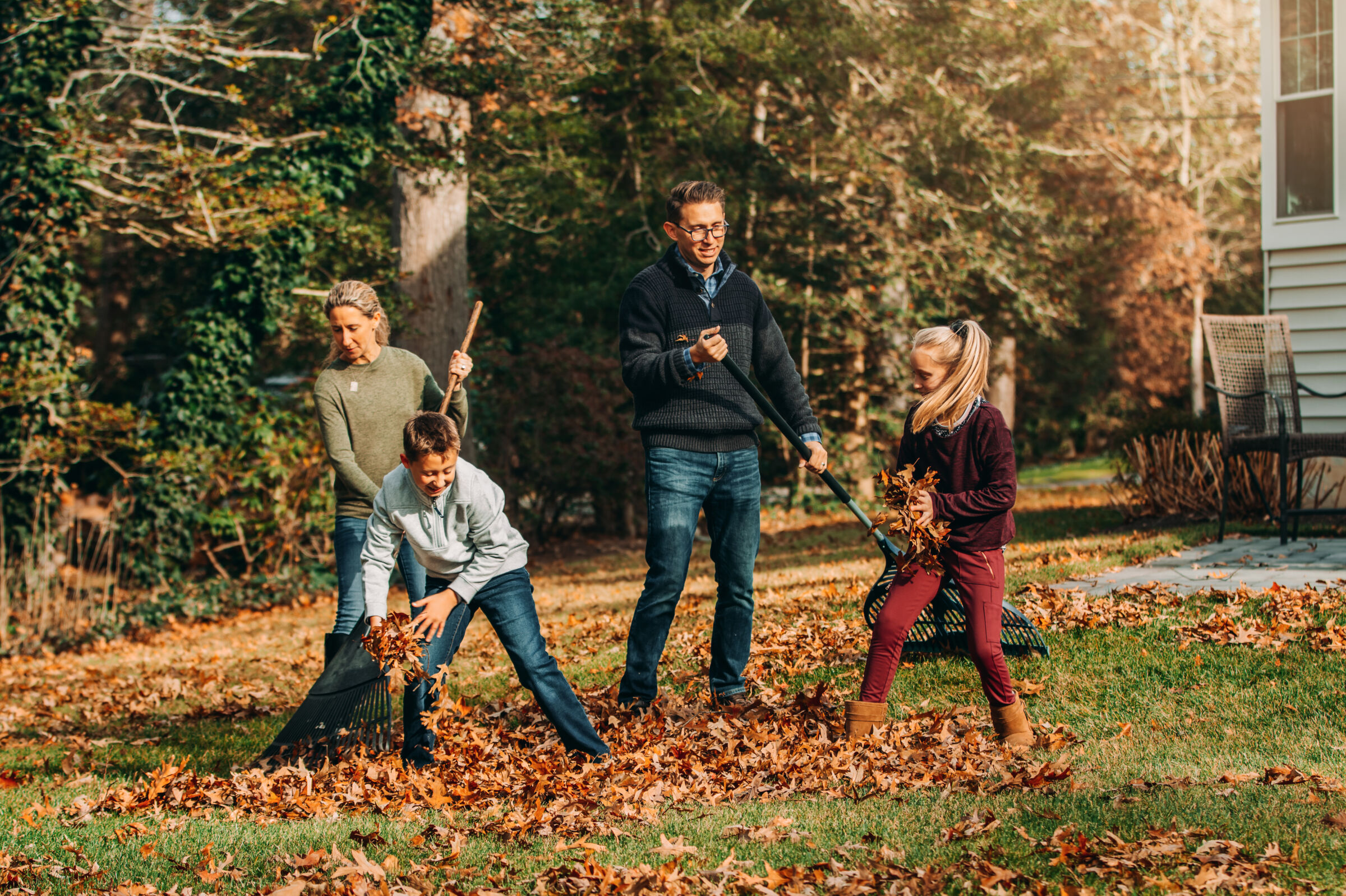 Family raking and playing in the fall leaves