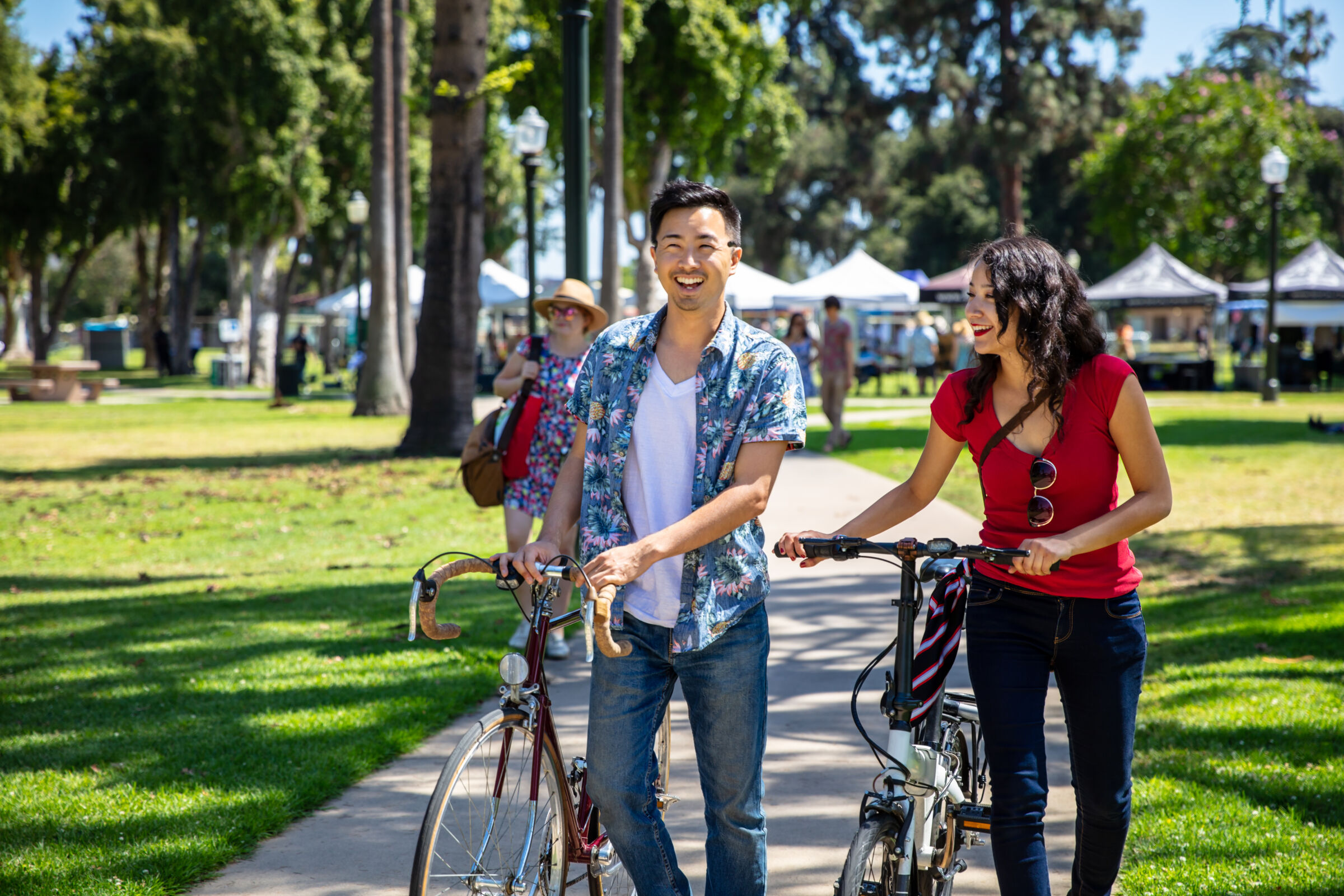 Couple walking their bikes in a park