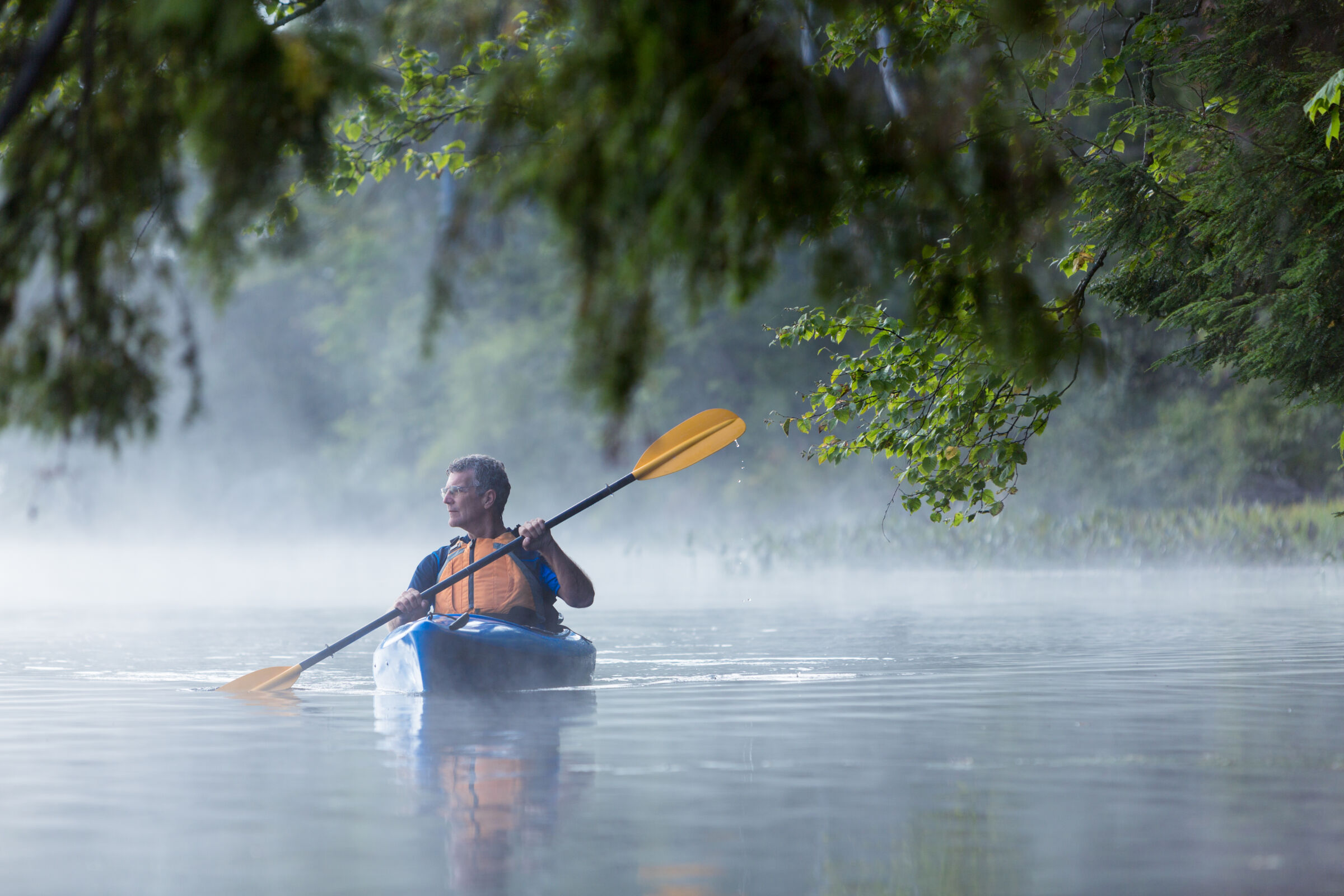 Man kayaking on foggy water