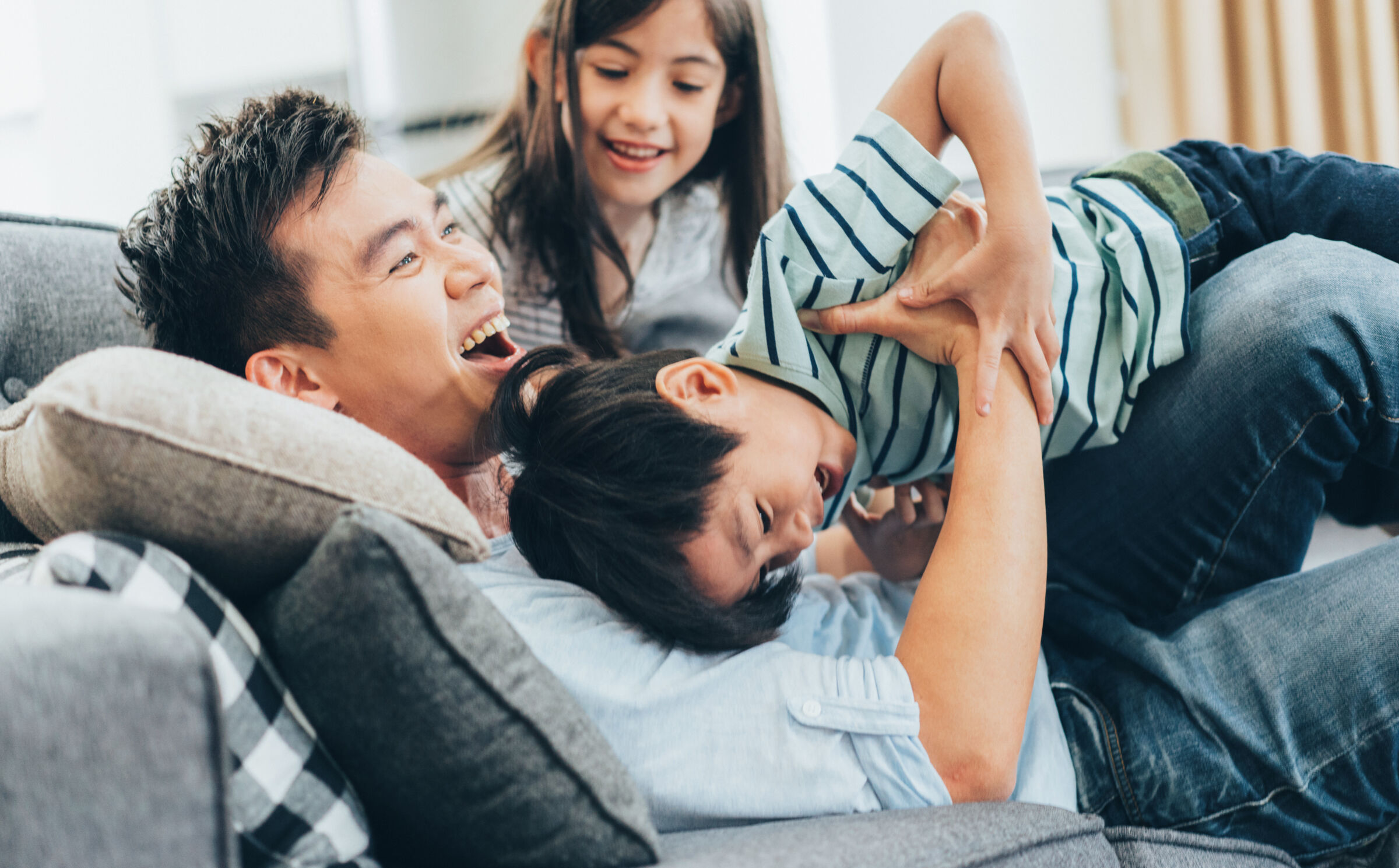 Family play wrestling on couch