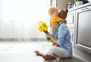 Mom and toddler hugging with flowers