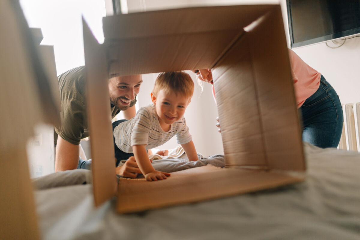 Parents and toddler playing with cardboard box