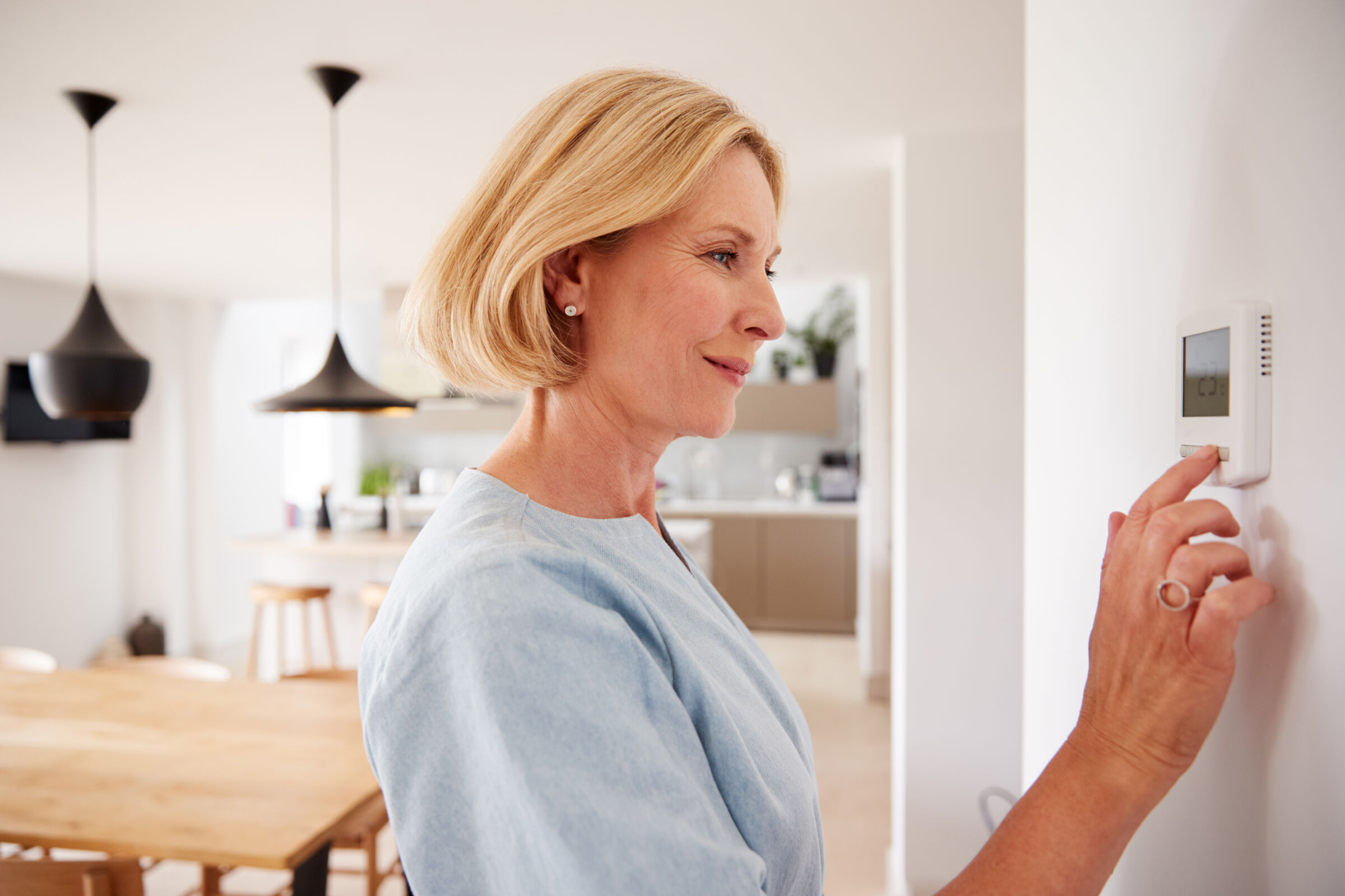 Senior woman adjusting the thermostat