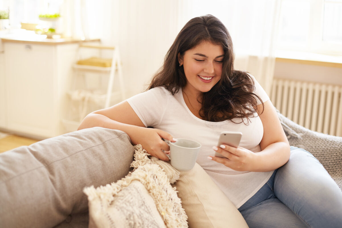 Young woman sitting on the couch on her phone