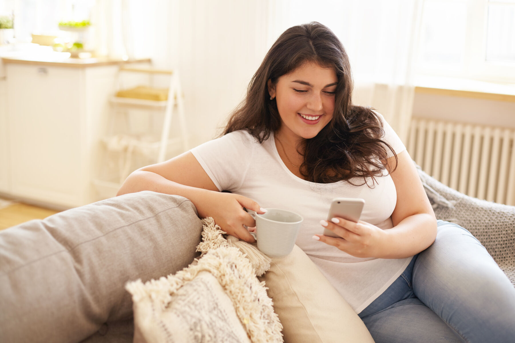 Young woman sitting on the couch on her phone