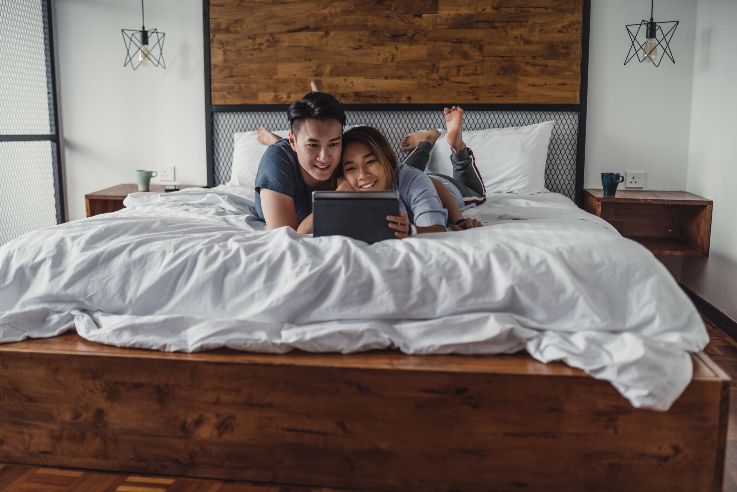 Young couple looking at a tablet in bed