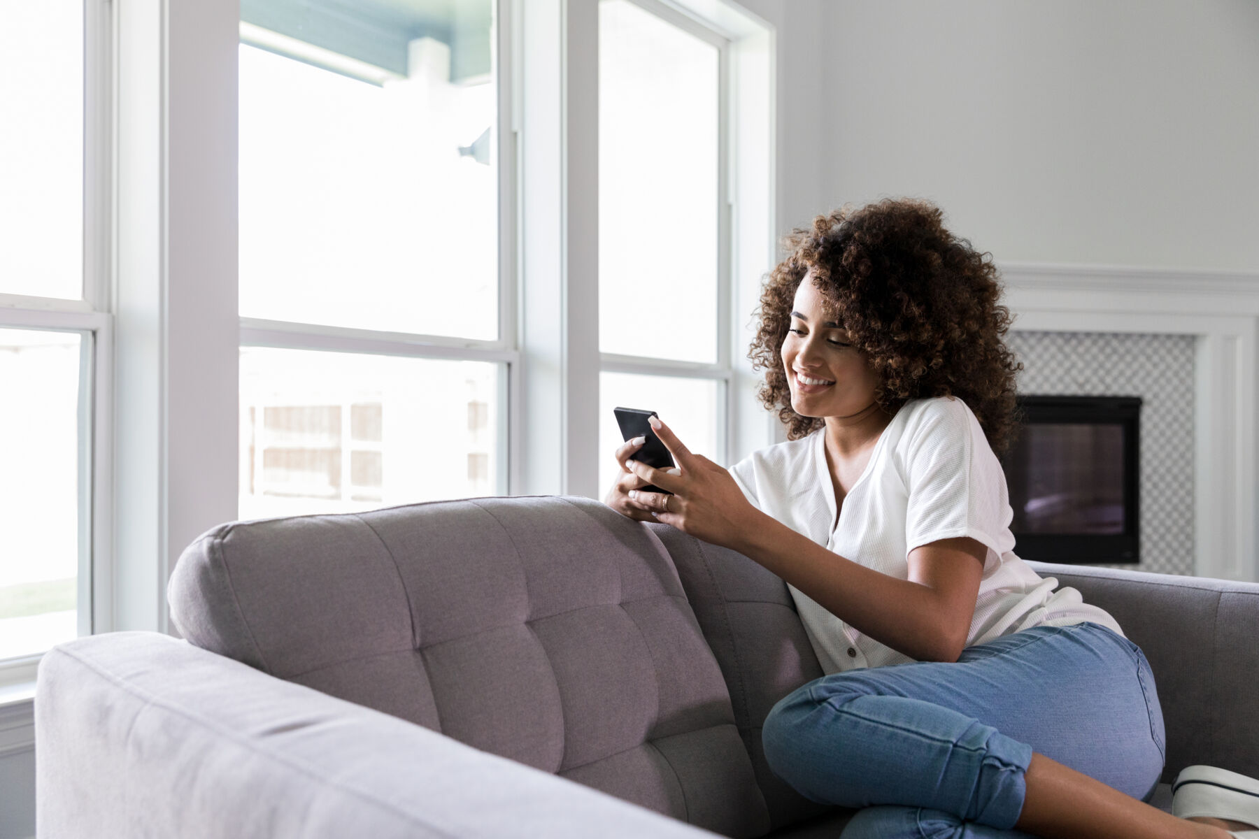 Young woman sitting on the couch on her phone