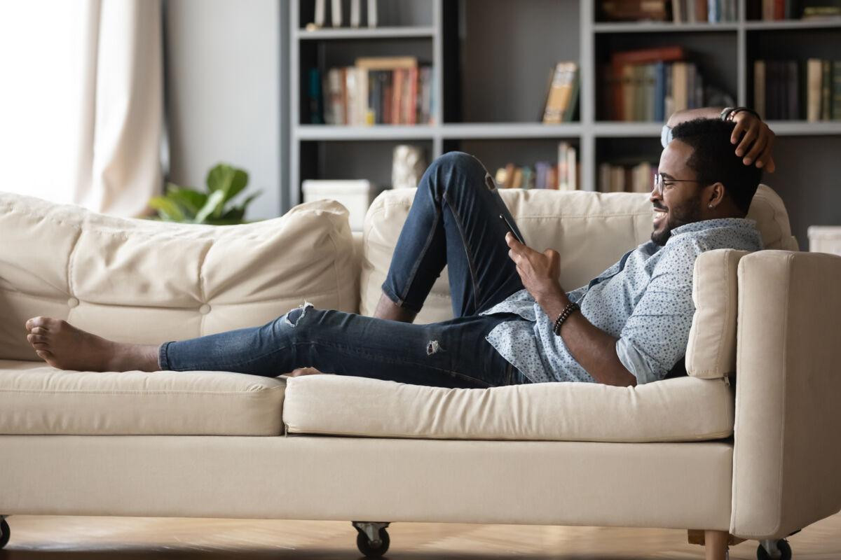 Man lounging on couch browsing on phone