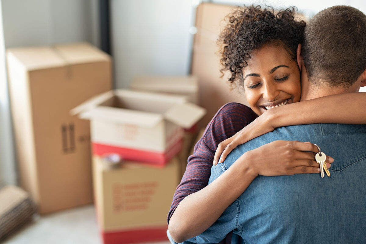 Couple hugging with keys and boxes
