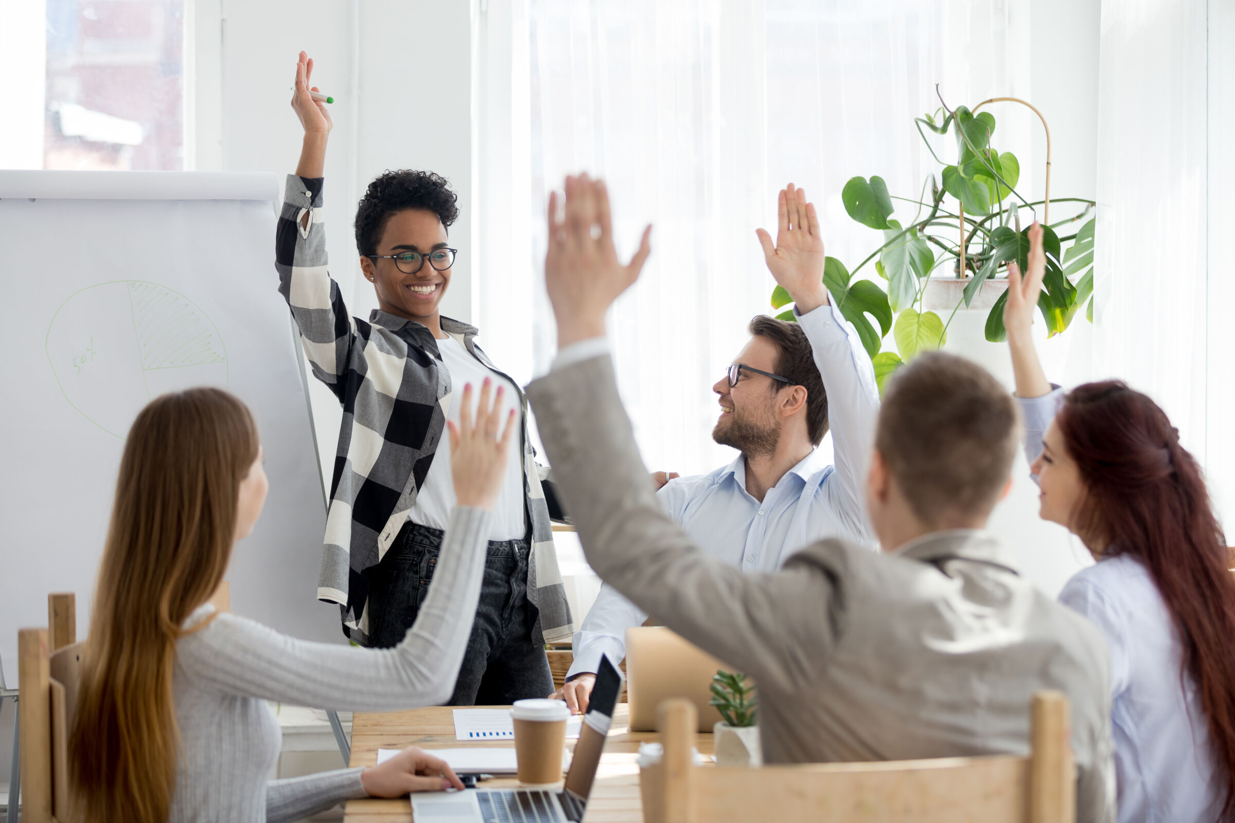 Group of workers raising hands in a meeting