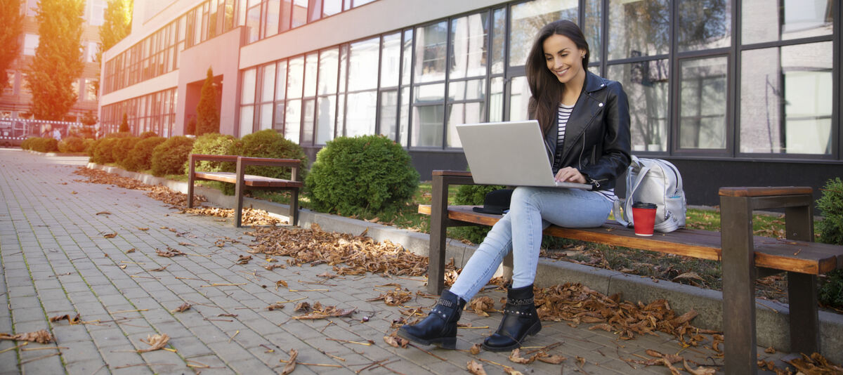 Woman working on a laptop on a bench