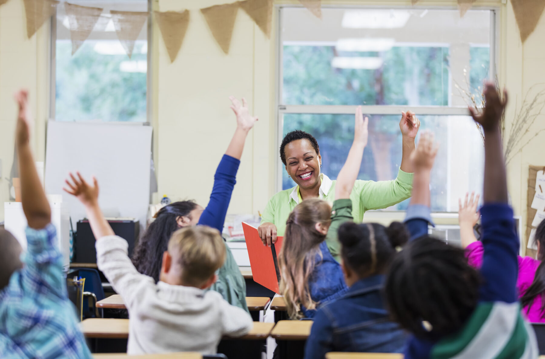 Group of kids raising their hands in a school classroom
