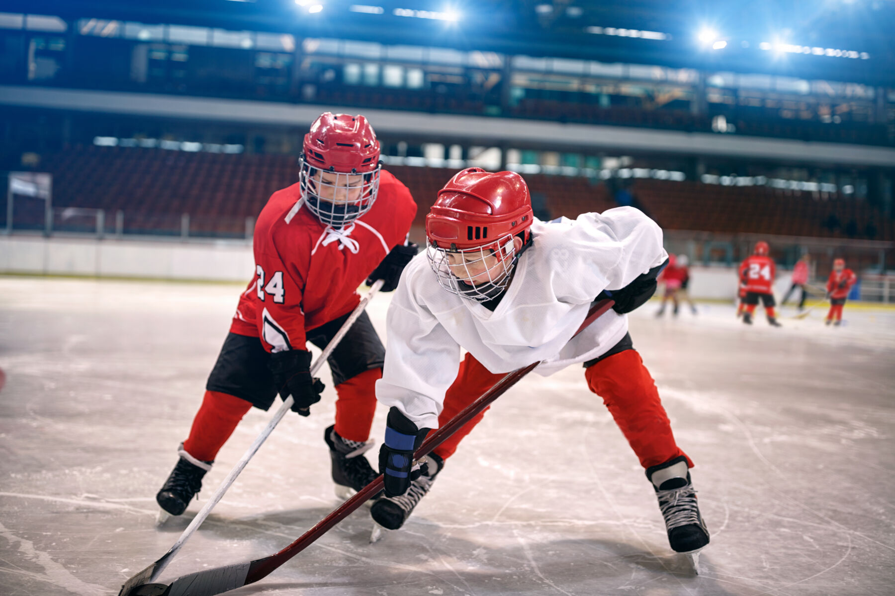 Two kids playing hockey in an arena