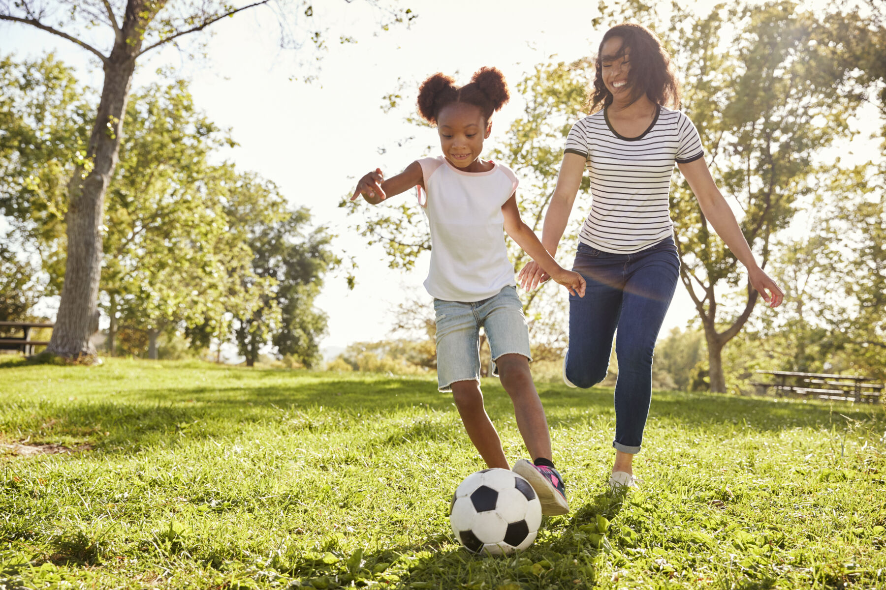 Mother and Daughter Playing Soccer Outside in the Backyard on a Sunny Day