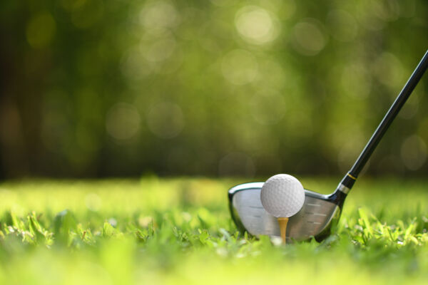 Closeup shot of a golf club and a golf ball teed up for a drive.