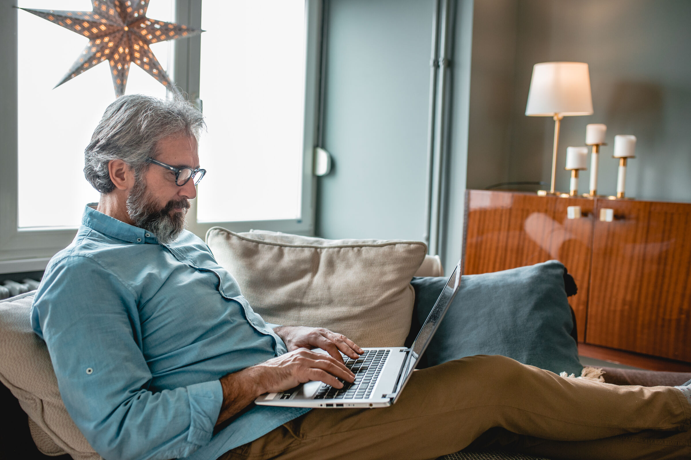 older man working on computer on the couch
