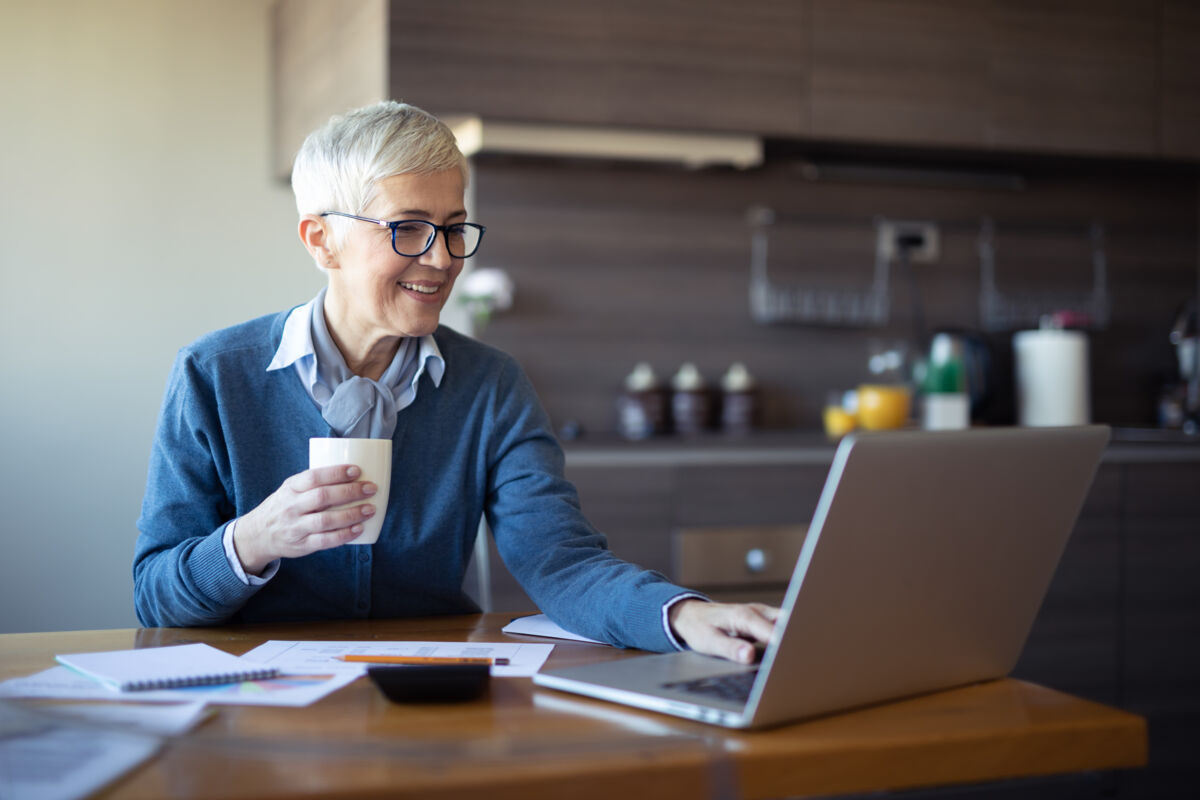 older woman working on computer at dining table
