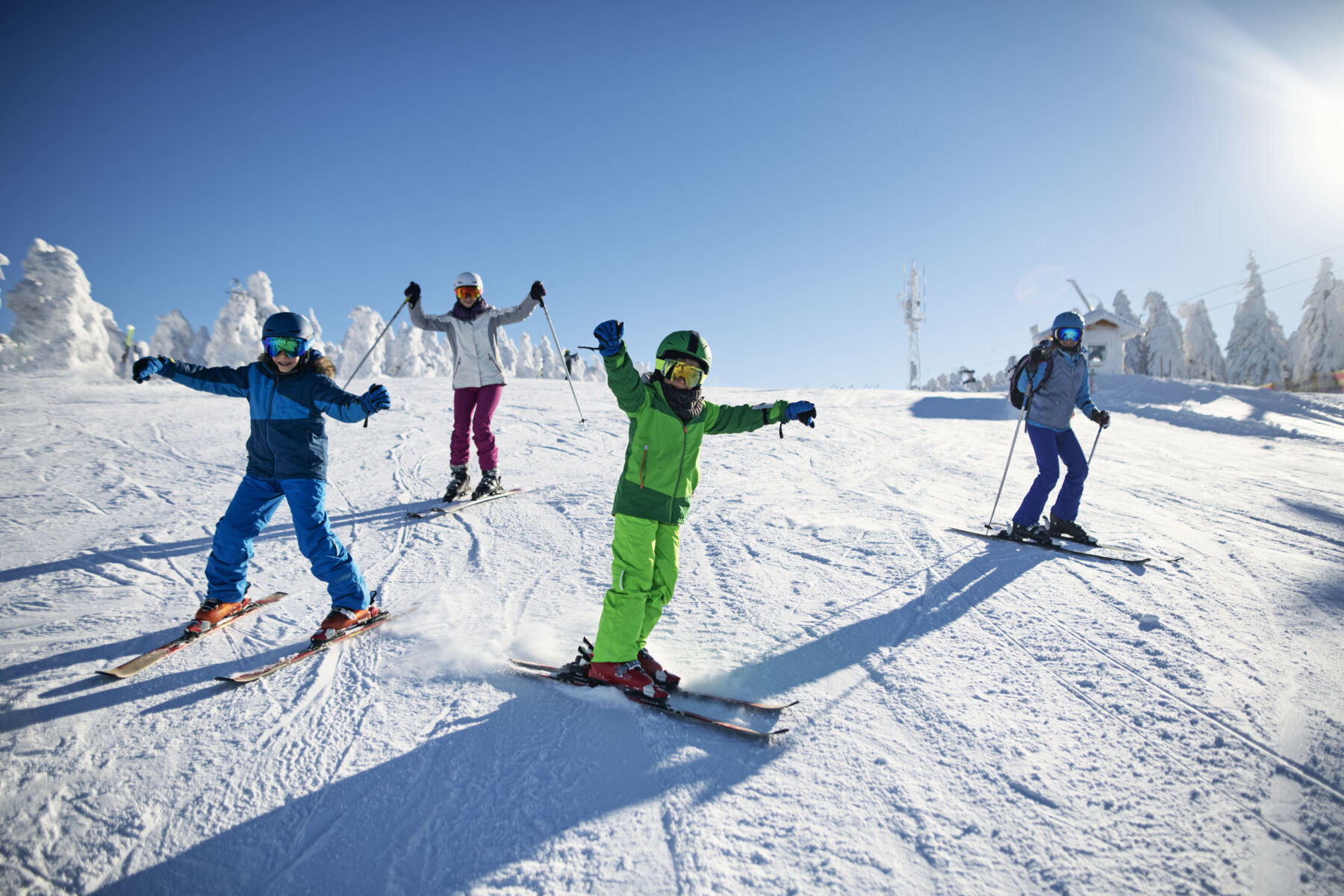 A family skies down the snowy mountain on a sunny, clear day.