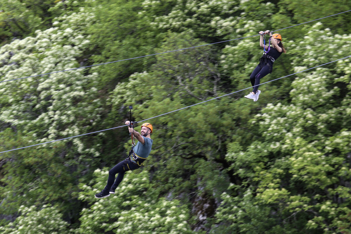 Man and woman on ziplines over trees