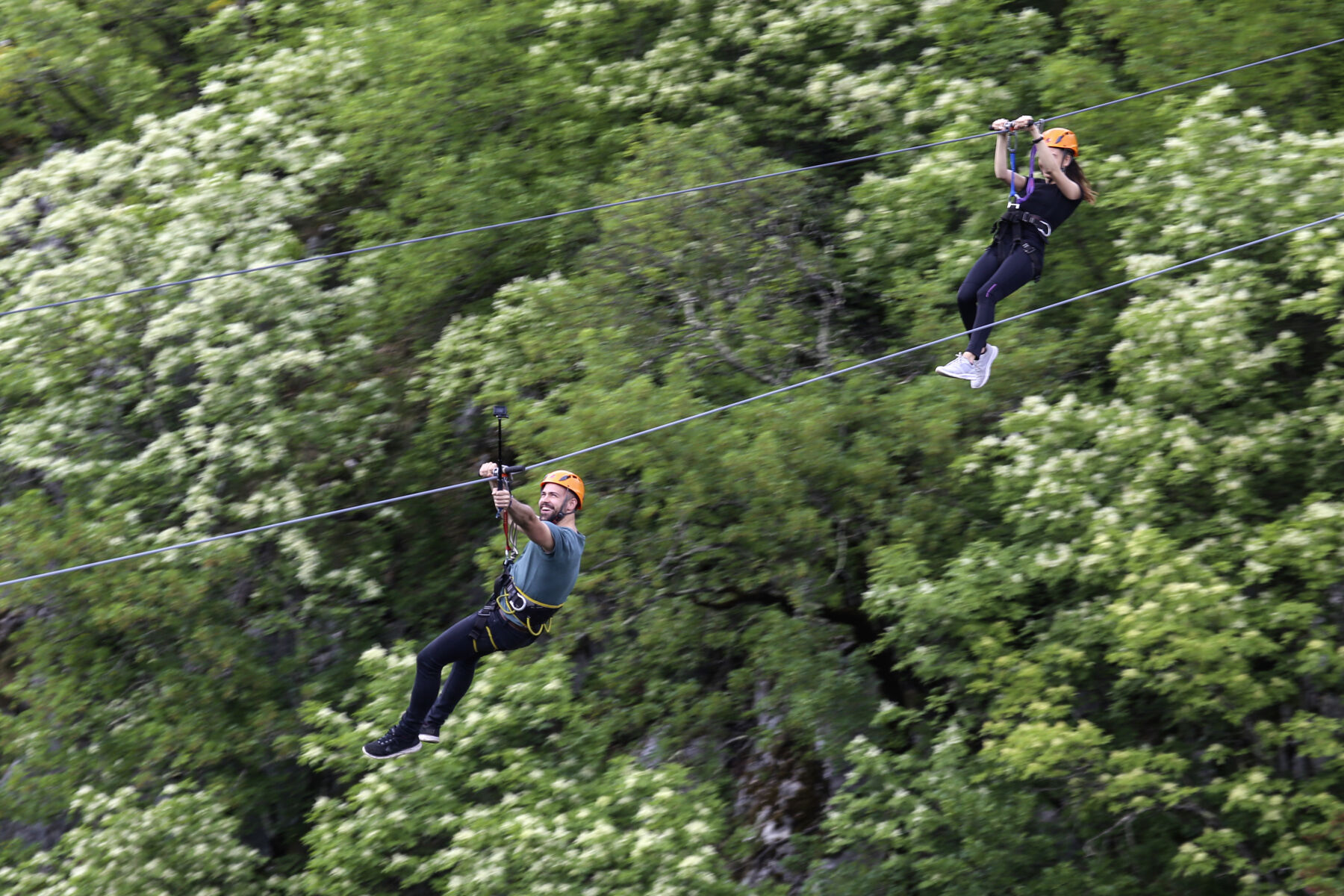 Man and woman on ziplines over trees