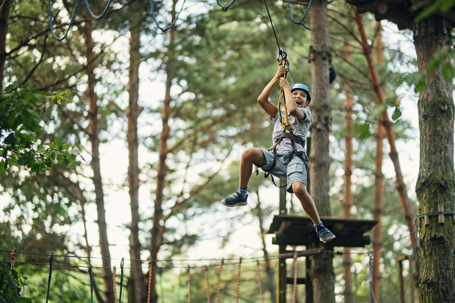 teen boy ziplining from platform