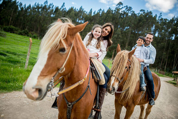 Family at the farm riding horses and looking happy