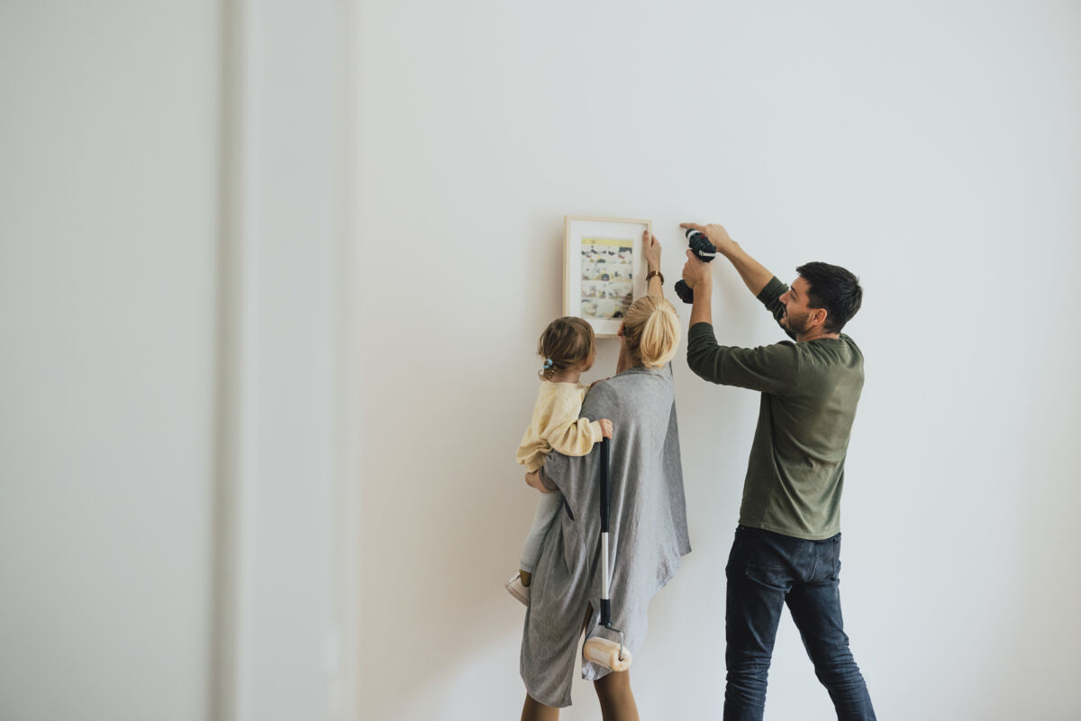 Couple With Baby Hanging Picture on Wall