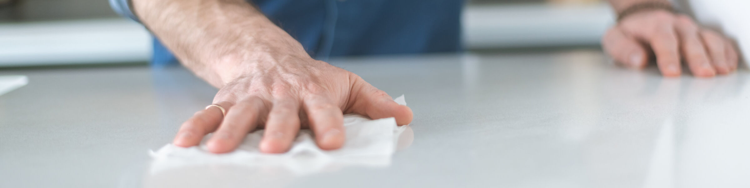 Person Wiping Countertops in Kitchen