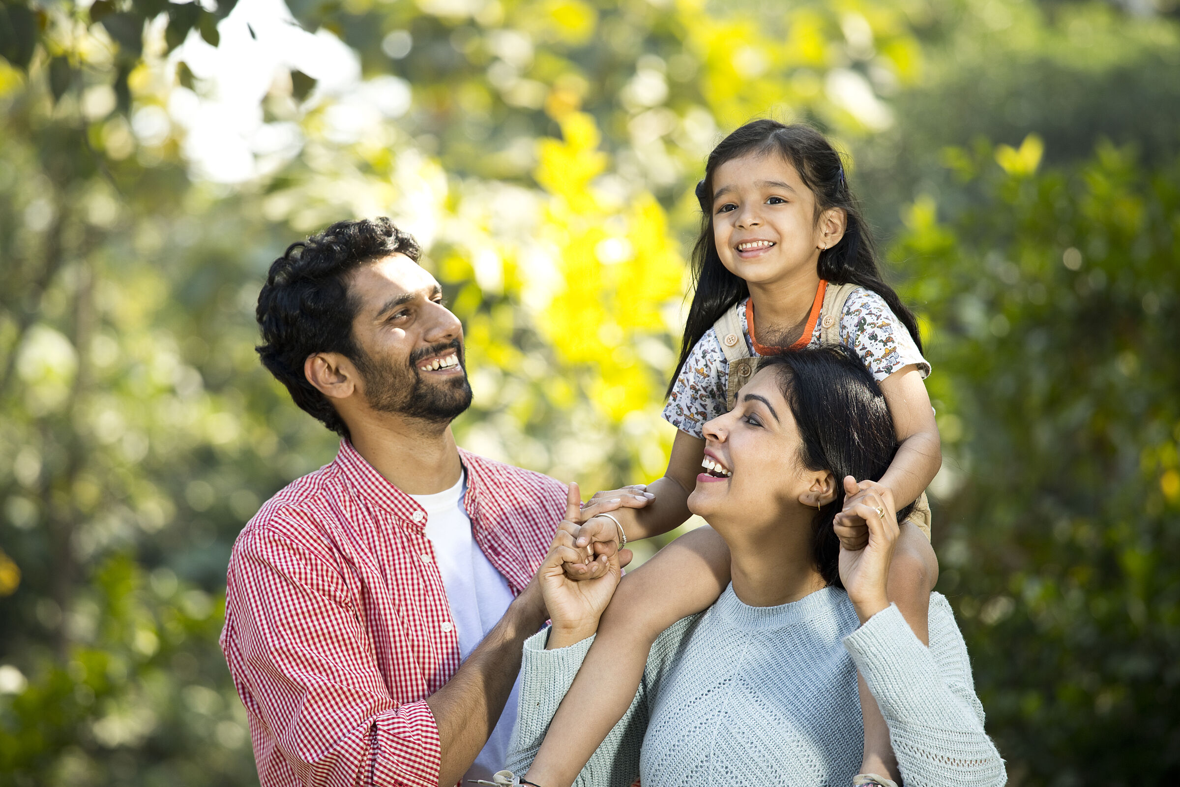 Family smiling, child on shoulders