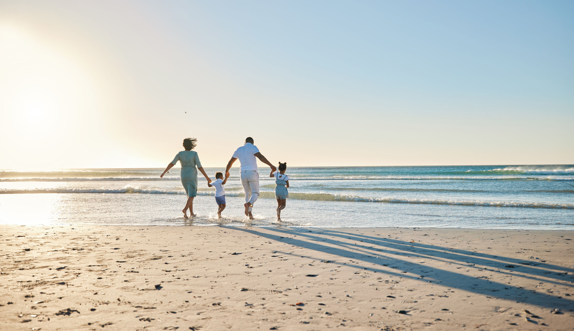 Family Running Into Water on Beach