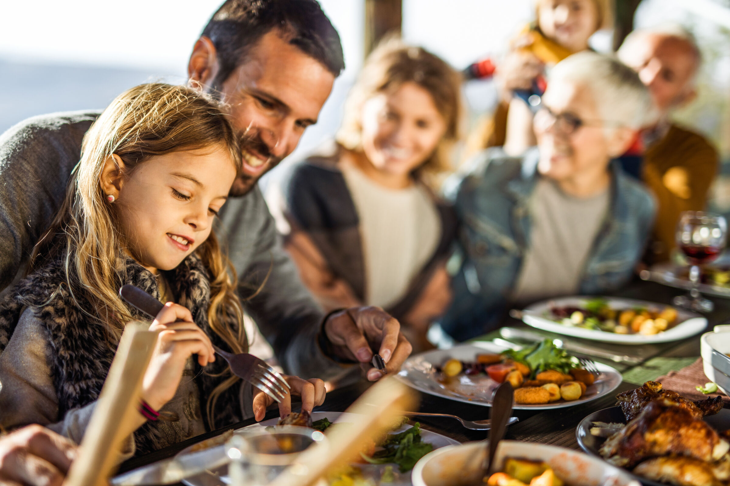 A young girl, her dad, and her family eating lunch at a restaurant