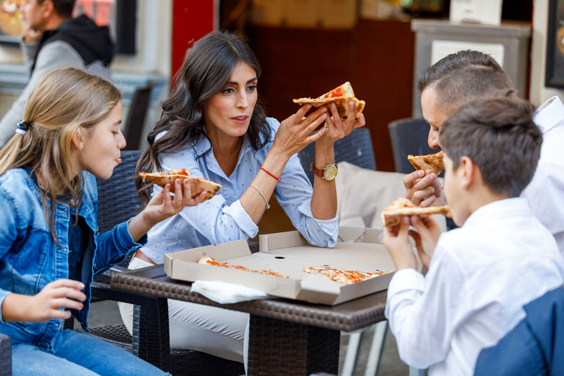Family eating pizza at a restaurant outside